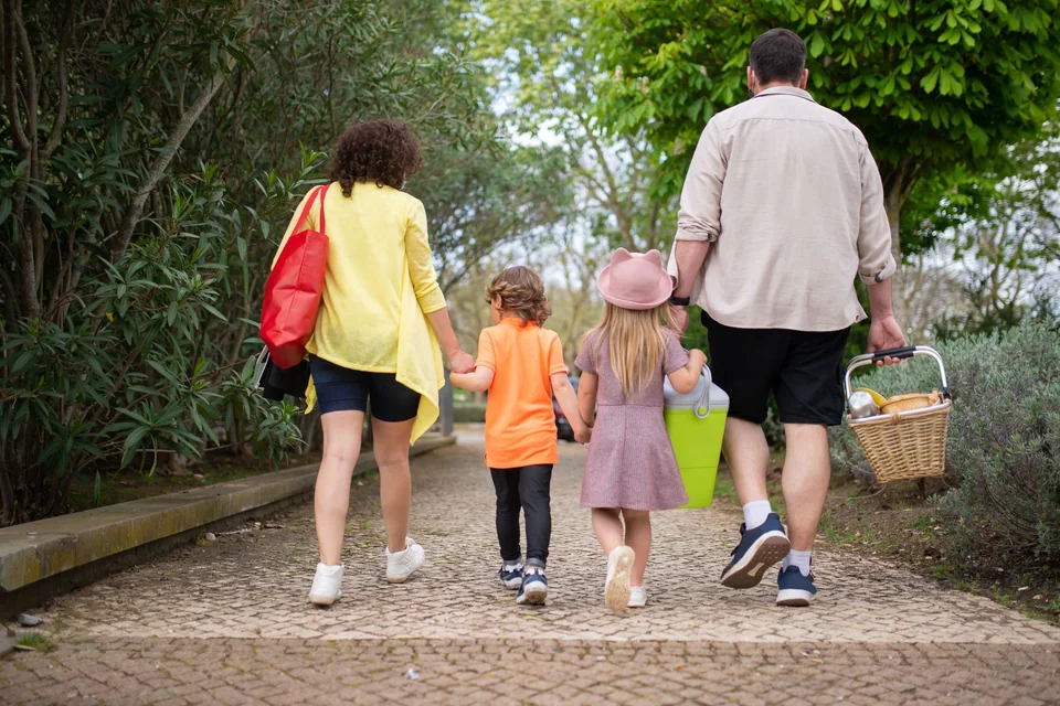 A family walking together along a grassy path in a park on a sunny afternoon.